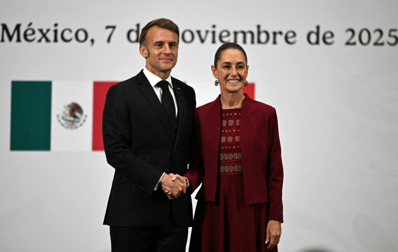 El presidente de Francia, Emmanuel Macron (izq.), y la presidenta de México, Claudia Sheinbaum, se dan la mano durante una conferencia de prensa conjunta en el Palacio Nacional de la Ciudad de México el 7 de noviembre de 2025. (Foto de CARL DE SOUZA / AFP)