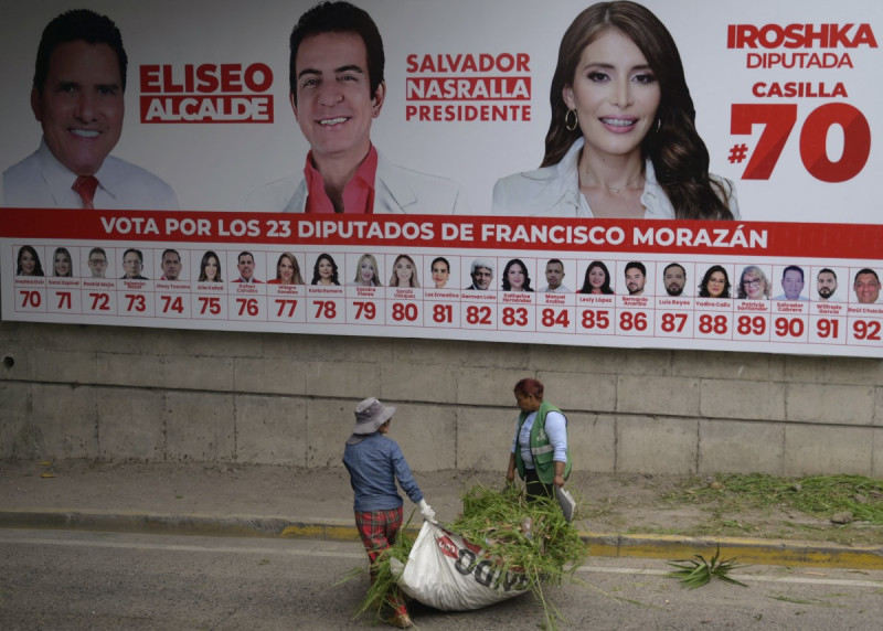 Indígenas caminan frente a una valla publicitaria del candidato presidencial Salvador Nasralla, del Partido Liberal, en Tegucigalpa, el 5 de noviembre de 2025.