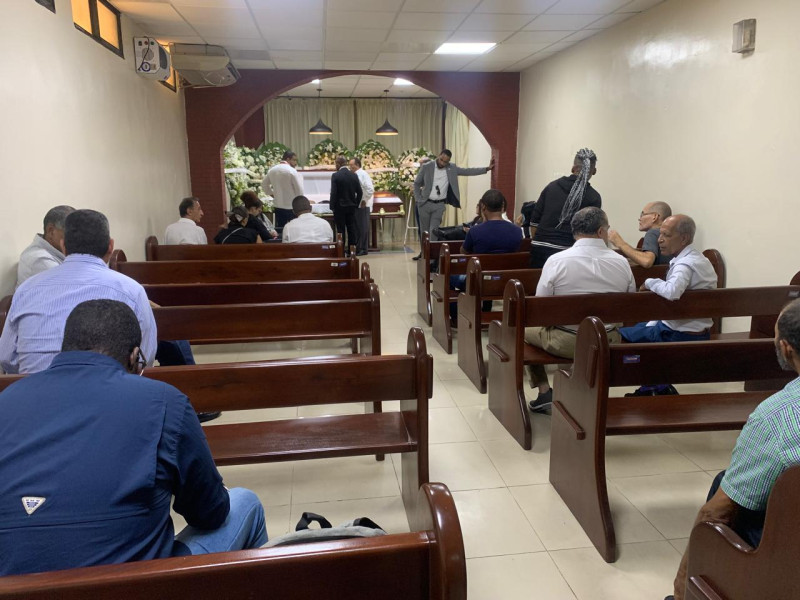 El féretro que contiene los restos de Tomás Julián Cabrera, rodeados de coronas de rosas y varias personas en la primera hora que fue expuesto en la Funeraria Savica,