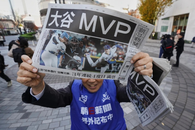 Personal del periódico japonés The Asahi Shimbun sostiene una copia de la edición extra con el anuncio del MVP a Shohei Ohtani de los Dodgers de Los Ángeles.