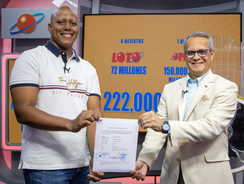 El licenciado Manuel Abreu, director de Sorteos de Leidsa, entrega un certificado al joven Alinson Rolando Dipré, ganador del premio de 222 millones de pesos correspondiente a la Loto del pasado sábado.