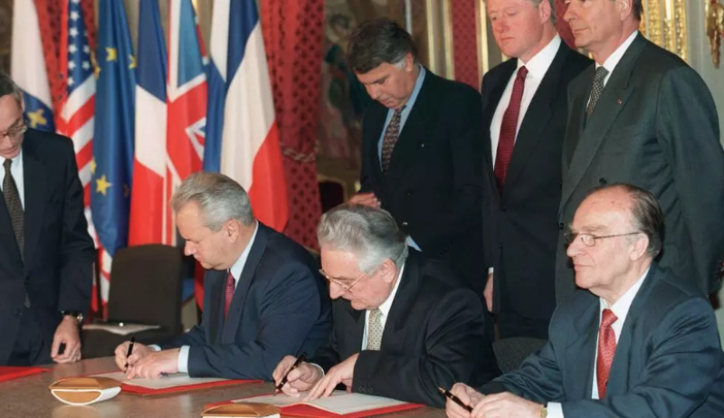El presidente serbio Slobodan Milošević (izq.), el presidente bosnio Alija Izetbegović (centro) y el presidente croata Franjo Tuđman (der.) firman los Acuerdos de paz de Dayton sobre Bosnia, bajo la mirada (2.ª fila, de izquierda a derecha) del presidente del Gobierno español Felipe González, el presidente estadounidense Bill Clinton y el presidente francés Jacques Chirac, el 14 de diciembre de 1995 en París.