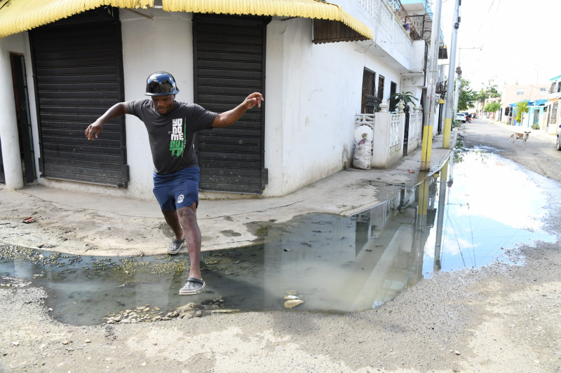 Vecino del sector El Almirante Caña mientras cruzando cúmulo de agua contaminada.