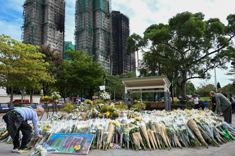 Los dolientes depositan flores para rendir homenaje a las víctimas en un monumento improvisado frente a los edificios de apartamentos del Tribunal Wang Fuk, tras el mortífero incendio del 26 de noviembre en el distrito de Tai Po, Hong Kong, el 1 de diciembre de 2025.