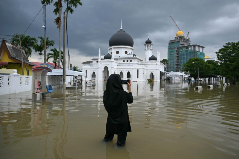 Una mujer toma una fotografía de una mezquita inundada en Kangar, en el estado de Perlis, al norte de Malasia.