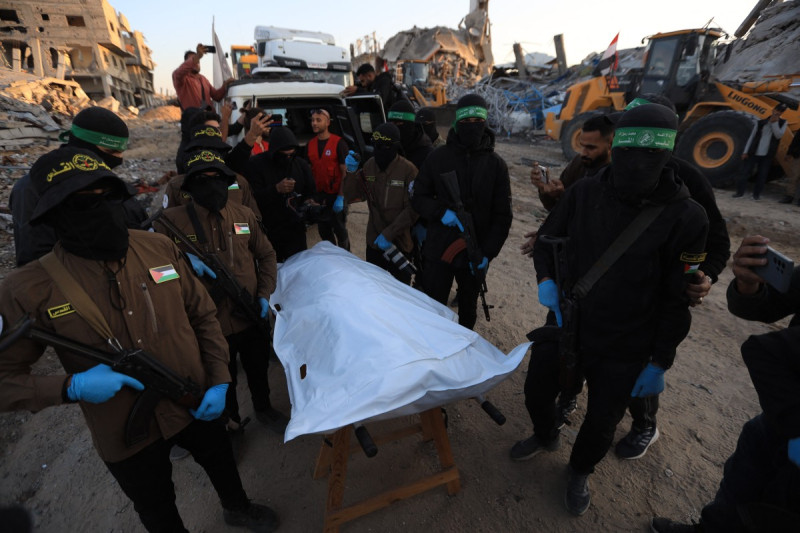 Militantes de la Yihad Islámica y Hamás junto a una bolsa blanca para cadáveres que se cree contiene los restos de un rehén israelí en la ciudad de Beit Lahia, en el norte de la Franja de Gaza, el 3 de diciembre de 2025.