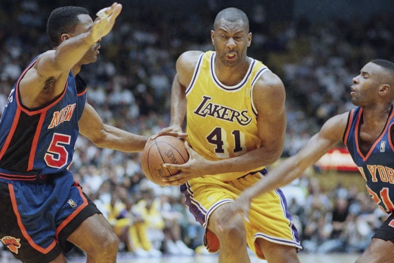 Elden Campbell, de los Lakers, penetra  mientras Buck Williams se retira y Charlie Ward, de los Knicks, defiende, en partido del 23 de febrero de 1997 en Inglewood.
