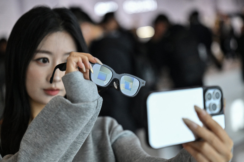 Esta fotografía, tomada el 13 de noviembre de 2025, muestra a una mujer revisando unas gafas Rokid con pantalla y cámara mediante inteligencia artificial (IA) y realidad aumentada (RA) durante una presentación en Hangzhou, provincia de Zhejiang