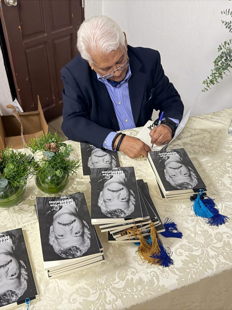 Ernesto Quiñones, mientras dedica su libro a algunos de los asistentes al acto.