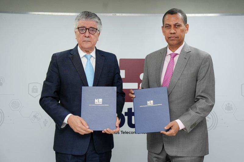 Guido Gómez Mazara, presidente del Consejo Directivo de Indotel, y Roberto Santana Sánchez, director de Onaprep, muestran el acuerdo firmado.
