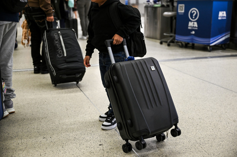 Andy, un ciudadano estadounidense de seis años, lleva su maleta mientras es escoltado, junto con otros seis niños, desde el Aeropuerto Internacional de Miami a Guatemala
