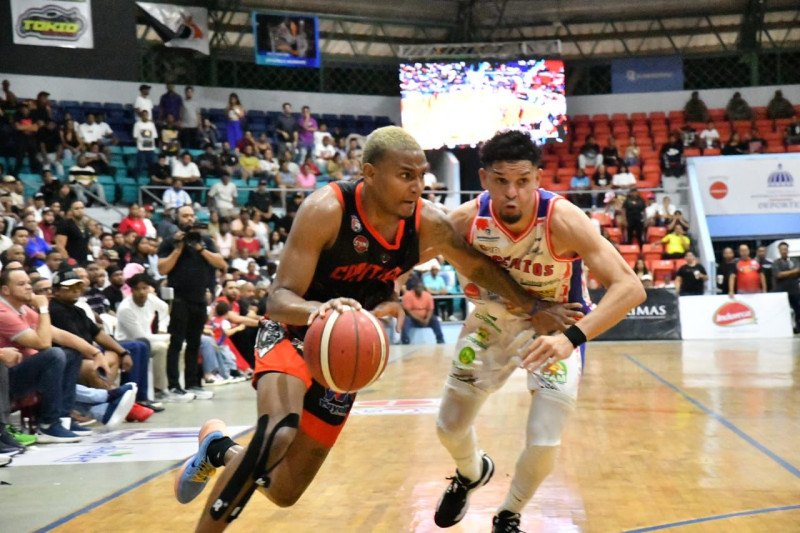 Diego Colón, de La Villa, maneja el balón mientras es defendido por Víctor Martínez, del Dosa, en el cuarto partido de la final del TBS de La Vega, el 14 de diciembre de 2025.