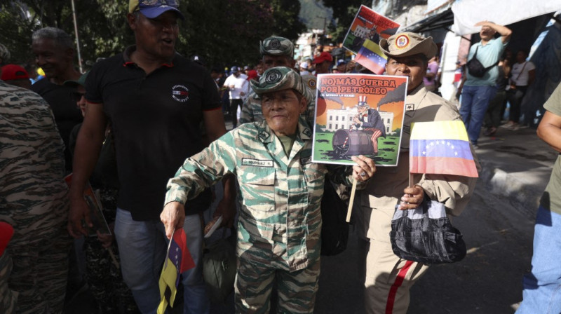 Partidarios del presidente Nicolás Maduro y miembros de la Milicia Civil Bolivariana participan en una protesta contra Estados Unidos con pancartas que dicen "No más guerra por el petróleo" en el barrio obrero de Petare, Caracas, Venezuela.