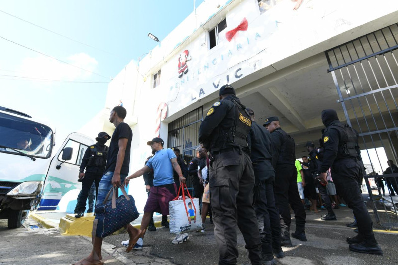 Reclusos de La Victoria caminan con sus pertenencias hacia autobuses en los que fueron trasladados a la nueva cárcel de Las Parras.