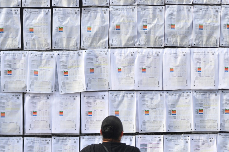 Una mujer observa el "muro de la victoria" del alcalde de Tegucigalpa y candidato a la reelección, Jorge Aldana, afuera del Centro de Logística Electoral, ubicado en el Instituto Nacional de Formación Profesional (INFOP), donde se realizará el recuento de las papeletas con inconsistencias en Tegucigalpa el 19 de diciembre de 2025.