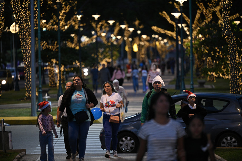 Personas caminan bajo los adornos navideños en el bulevar Los Próceres de Caracas el 19 de diciembre de 2025