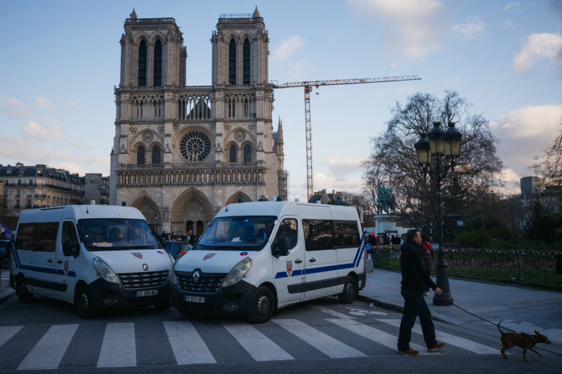 Un peatón pasea a su perro junto a las furgonetas policiales del Cuerpo de Seguridad Republicano francés, desplegadas para garantizar la seguridad en los alrededores del centro de París, en la víspera de Navidad