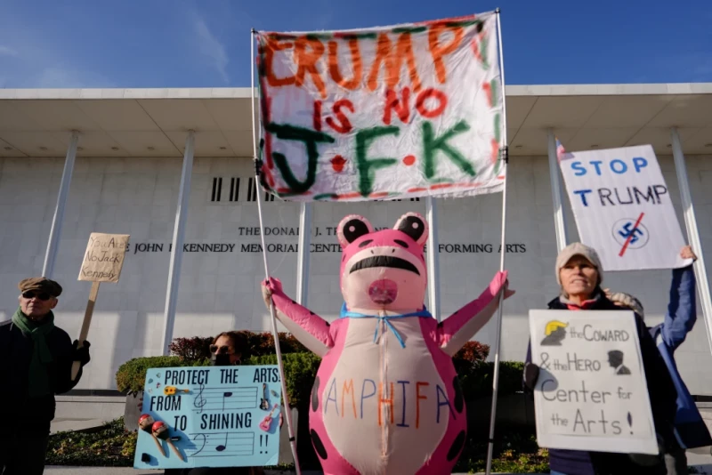 Nadine Siler, de Waldorf Maryland, disfrazada de rana rosa, y otros manifestantes sostienen pancartas durante una protesta frente al Centro John F. Kennedy para las Artes Escénicas.