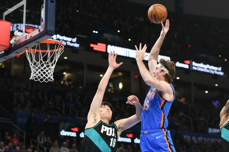Branden Carlson (15), del Thunder de Oklahoma City, dispara sobre Yang Hansen (16), de los Trail Blazers de Portland, durante la segunda mitad del juego.
