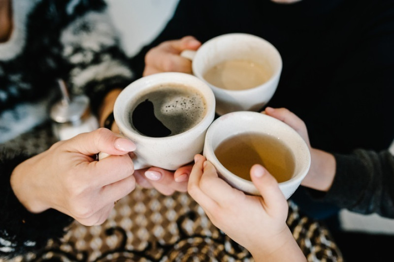 Manos sosteniendo tazas de café y té por la mañana.
