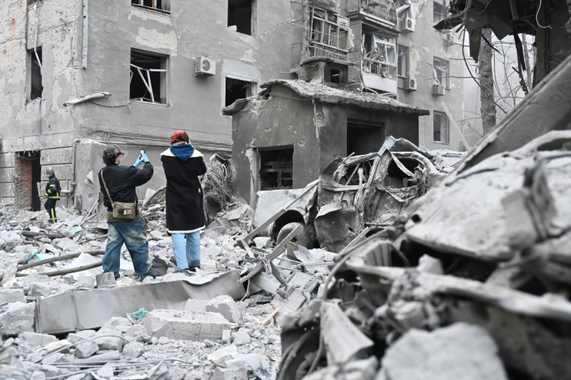 Residentes locales toman una fotografía de edificios residenciales dañados tras un ataque aéreo ruso en Járkov el 2 de enero de 2026, durante la invasión rusa de Ucrania.