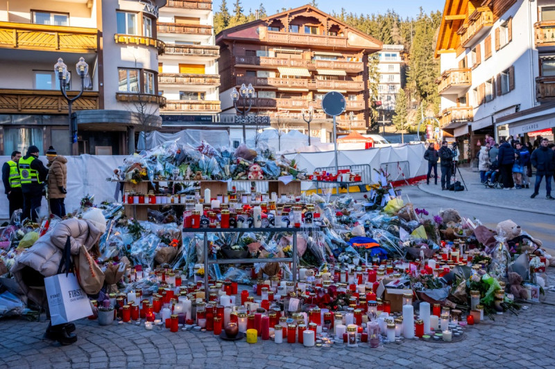 Una persona de luto deposita un ramo de flores en un monumento improvisado cerca del bar Constellation, el 4 de enero de 2026, en Crans-Montana, en honor a las víctimas del incendio que arrasó el local en la lujosa estación de esquí alpino la víspera de Año Nuevo.
Las autoridades que investigan el incendio de Año Nuevo en la estación suiza de Crans-Montana han identificado a 24 de las 40 personas fallecidas, entre ellas 11 menores y seis extranjeros, según informó la policía el 4 de enero de 2026. Además, 119 personas resultaron heridas durante el incendio, la mayoría de ellas de gravedad, según el último balance.