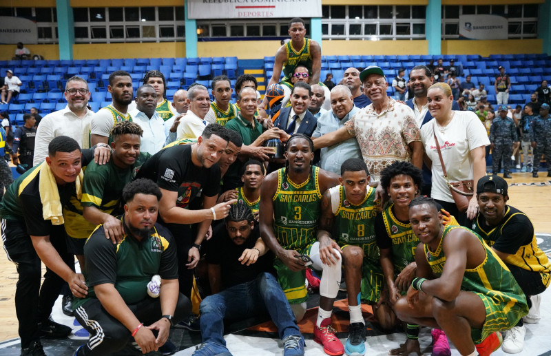 Robinson Portorreal y Óscar Peña Oscar Peña, del Banreservas, entregan la Copa Banreservas a Agustín Espinosa, directivo del club San Carlos, en compañía de Leo Corporán, Fernando Geraldino y José Boyón Domínguez. En la gráfica los nuevos monarcas del Clásico de Baloncesto -Boyón- Domínguez posan sonrientes con su título de campeón.