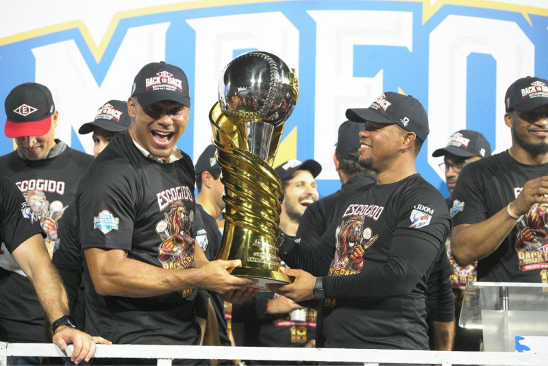 El gerente Carlos Peña y el dirigente Ramón Santiago sostienen el cetro de campeón de Lidom en la temporada 2025-2026.