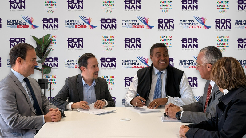 Roberto García, ejecutivo de Bornan Sports Technology, y José P. Monegro, presidente del Comité Organizador de los Juegos Santo Domingo 2026 durante la firma del acuerdo. Los acompañan, Carlos Iglesia, Luis Mejía Oviedo y Mercedes Canalda.