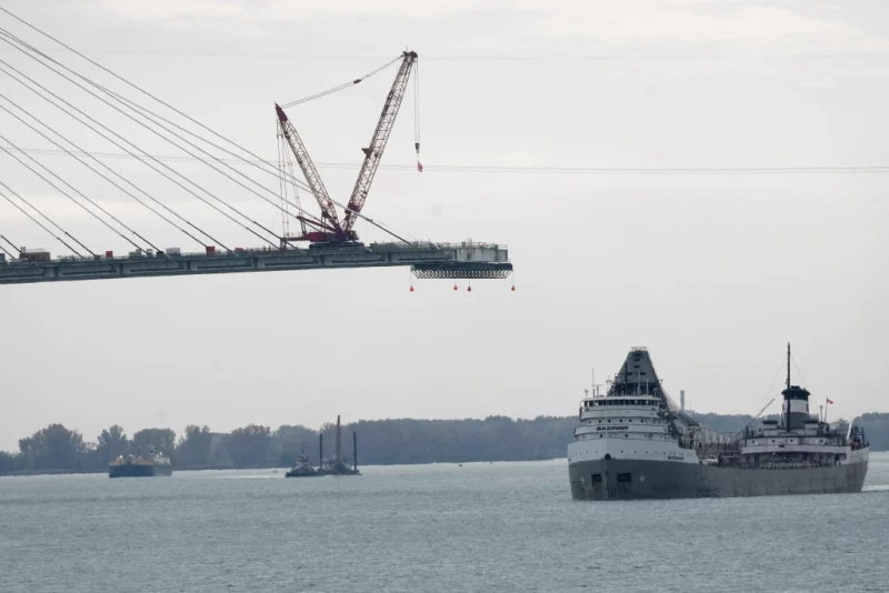 El barco Saginaw pasa frente a la construcción del Puente Internacional Gordie Howe, que pasa sobre el río Detroit y une Windsor, Ontario, con Detroit, el 25 de octubre de 2023.