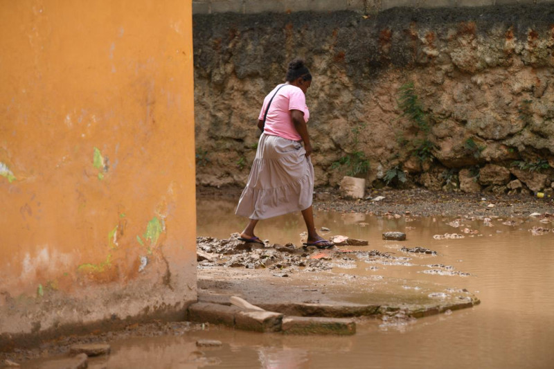 Comunitaria intenta cruzar sobre piedras la laguna formada por agua posada en el sector Nancy Nadesha.