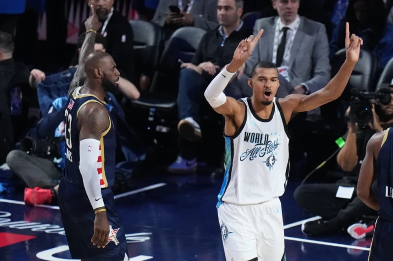 Victor Wembanyama, del equipo del Mundo, reacciona al lado de LeBron James, del equipo de las Barras, en el Juego de Estrellas de la NBA, el 15 de febrero de 2026.