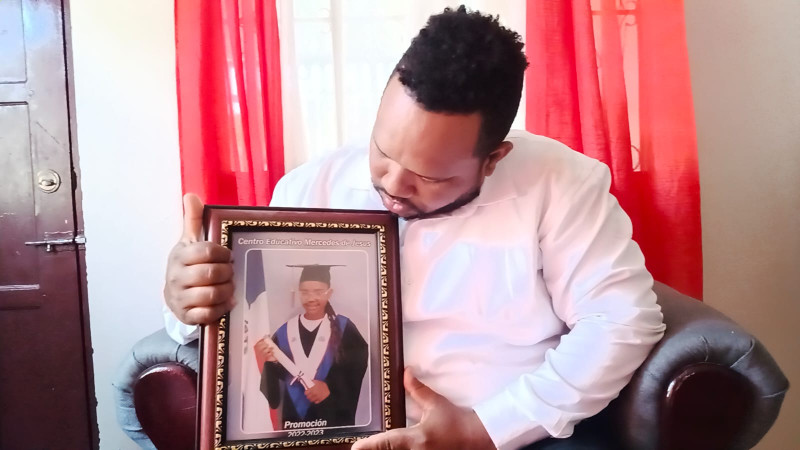 Rainer Alexander Feliz Novas sostiene una foto de su hija fallecida.