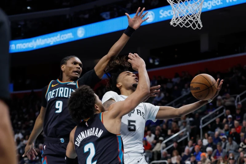 Stephon Castle, de los Spurs, se alza hacia la canasta frente a Ausar Thompson y Cade Cunningham, de los Pistons, durante el juego del 23 de febrero de 2026.