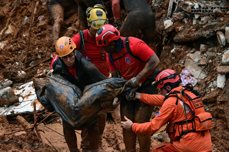 Bomberos cargan un cadáver hallado entre los escombros tras un deslizamiento de tierra causado por las fuertes lluvias en el Barrio Parque Jardim Burnier en Juiz de Fora, estado de Minas Gerais, Brasil.