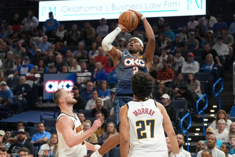 El base de los Oklahoma City Thunder, Shai Gilgeous-Alexander, arriba, dispara por encima del base de los Denver Nuggets, Christian Braun, a la izquierda, y al base Jamal Murray (27) durante la segunda mitad del partido.