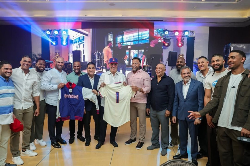 Kelvin Cruz, Nelson Cruz y Albert Pujols entregan chaquetas y una gorra al comisionado Rob Manfred. Observan los inmortales Adrian Beltré y Vladimir Guerrero, los jugadores Juan Soto, Vladimir Guerrero Jr. y Manny Machado, así comoJuan Núñez, Junior Noboa y Miguel Medina.