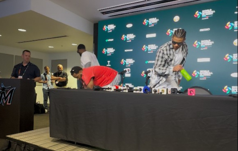 Vladimir Guerrero Jr. y Juan Soto retiran de la mesa 3 botellas de Oi Ocha de la mesa de conferencia de prensa