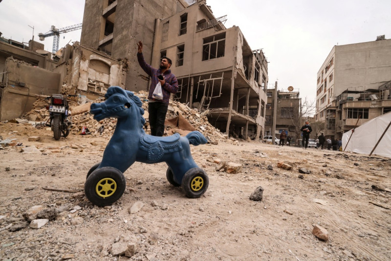 Un hombre iraní gesticula mientras permanece de pie cerca de casas destruidas tras un ataque militar a la capital iraní, Teherán, el 15 de marzo de 2026.