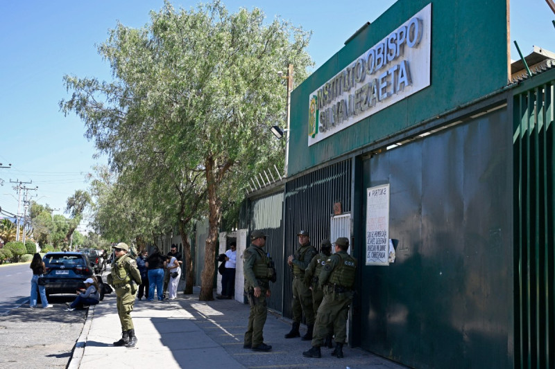 Familiares esperan afuera del Instituto Obispo Silva Lezaeta mientras la policía custodia la entrada luego de que un estudiante armado atacara a compañeros y maestros en Calama, norte de Chile, el 27 de marzo de 2026.