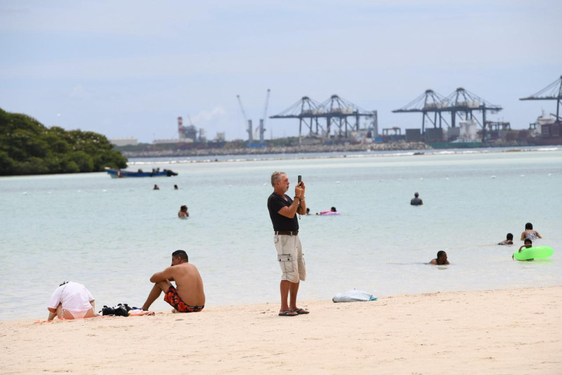 Un señor utiliza su celular para grabar el ambiente en la playa de Boca Chica el Jueves Santo.