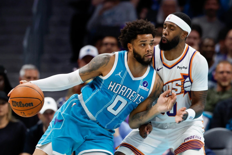 El ala-pívot de los Charlotte Hornets, Miles Bridges (0), embiste al ala-pívot de los Phoenix Suns, Royce O'Neale, durante la primera mitad de un partido de baloncesto de la NBA en Charlotte.