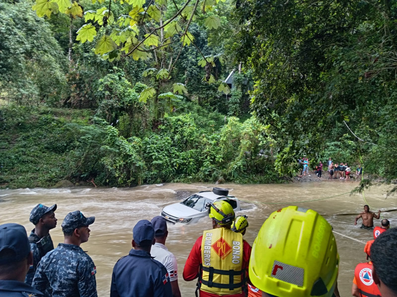 Miembros de los organismos de socorro ayudan a personas afectadas en crecida del río Tireo.