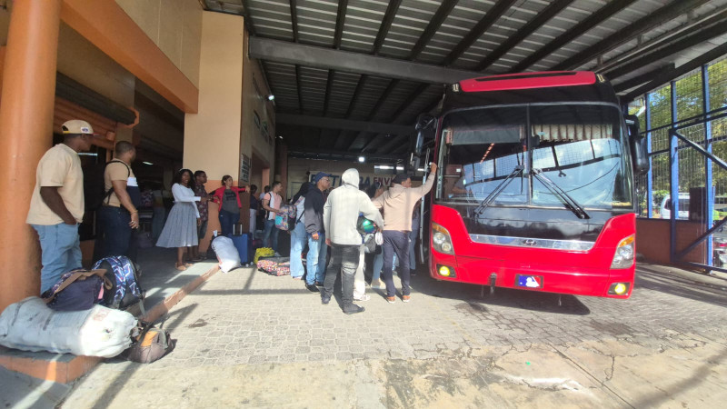 Viajeros buscan ingresar a una guagua para trasladarse de Barahona a Santo Domingo.