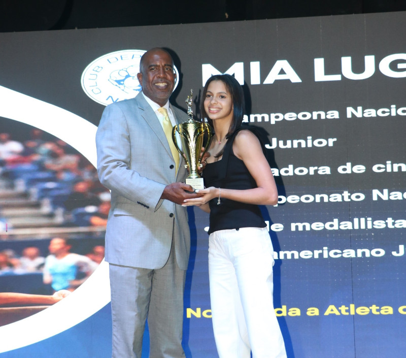 Claudio Guzmán, tesorero de la directiva del Club Naco, premia a Mia Lugo Valdez, de Gimnasia como "Atleta del Año" 2025.
