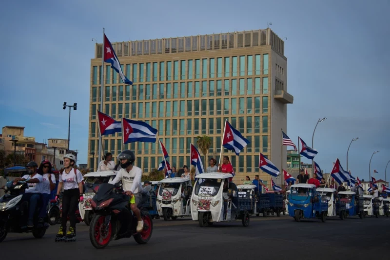 Varias personas pasan en vehículos eléctricos frente a la embajada de Estados Unidos durante una marcha juvenil antiimperialista organizada por el gobierno en La Habana, Cuba, el jueves 2 de abril de 2026.