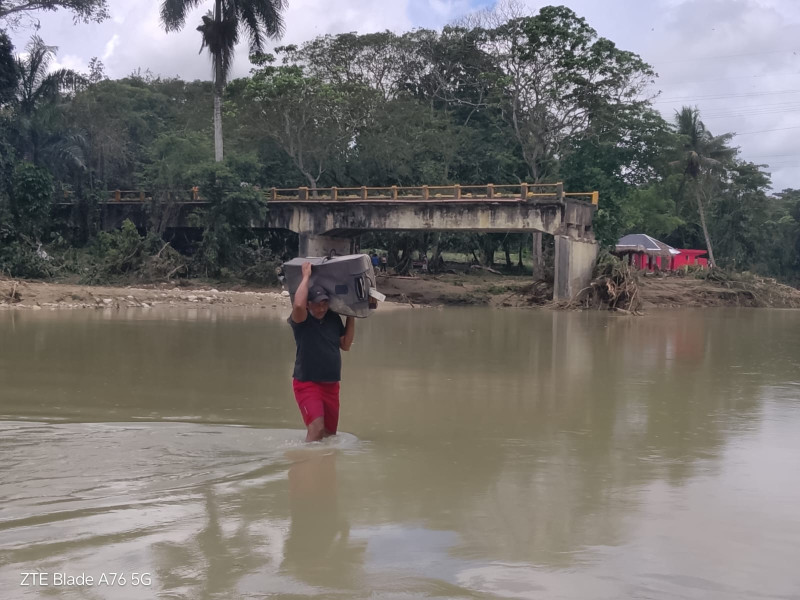 Un hombre cruza el río Camú, luego que las lluvias hicieran colapsar el puente