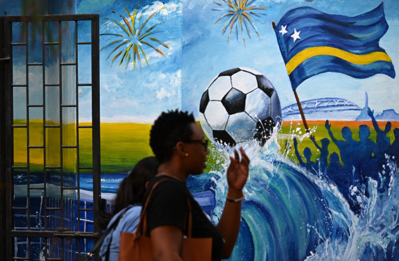 Mujeres caminan junto a un mural que representa un balón de fútbol y la bandera de Curazao en Willemstad, en el Caribe neerlandés, el 10 de abril de 2026.