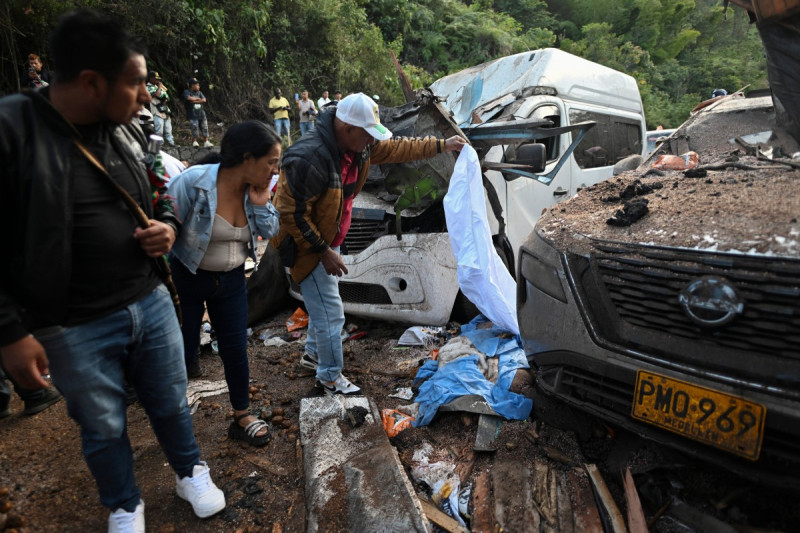 Imágenes de archivo / TOPSHOT - Varias personas se encuentran junto al cuerpo de una de las víctimas, cubierto con una sábana azul, tras un atentado con bomba en El Túnel, en la carretera Popayán-Cali, en Cajibio, departamento del Cauca, Colombia, el 25 de abril de 2026. Un atentado con bomba ocurrido el 25 de abril dejó siete muertos y 20 heridos en una zona de Colombia con una fuerte presencia guerrillera, en medio de una ola de ataques a poco más de un mes de las elecciones presidenciales, según informó el gobernador de la región del Cauca.
