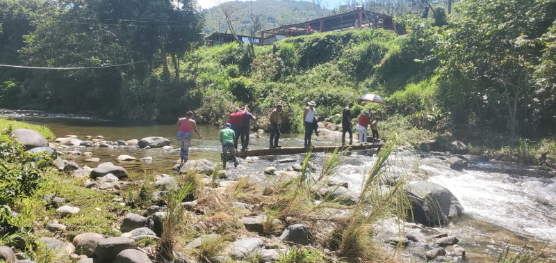 Personas cruzan río Mahoma sobre tablas en San José de Ocoa.
